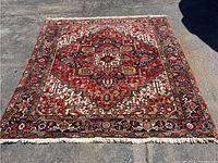 Full view of square wool rug laid flat, showing central medallion and border design