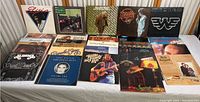 Top view of 14 vinyl record covers arranged on a table showing artists like Elvis Presley, Willie Nelson, Merle Haggard, Hank Williams, Ricky Skaggs, and more.