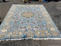 Full view of light blue Persian rug laid flat showing central medallion and border motifs