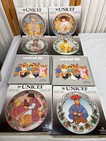 Full set of eight Villeroy & Boch UNICEF plates with original boxes, displayed with front view of each plate's box art illustrating child designs representing global cultures.
