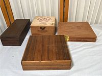 Four wooden gift boxes displayed on a white surface showing varied sizes and wood finishes.