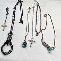 Full view of six vintage necklaces arranged on white background showing pendants and chains.