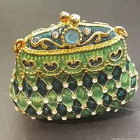 Front view showing blue rhinestone clasp and green enamel with gold and rhinestone lattice design.