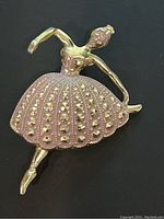 Front close-up photo showing the gold tone ballerina pin brooch with pink rhinestone-studded tutu and the dancer in a poised ballet position.