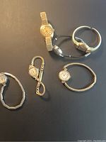 Top view of five vintage lady watches arranged on black surface showing different band styles and face shapes.