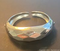 Top view of the silvertone hammered bangle bracelet showing the curved open cuff shape and textured surface.