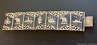Full view of vintage sterling silver niello panel bracelet with openwork borders and various animal and temple designs on each panel.