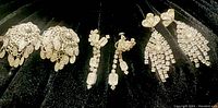 Photo showing three pairs of clear rhinestone vintage earrings in assorted drop styles on black velvet.