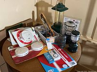 Photo showing smoke detectors, CO2 alarm, battery operated lanterns, and battery packs on round table