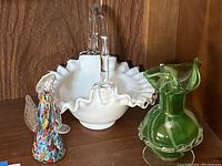 Photo depicting the hand blown glass angel figurine next to the white frilled handled glass bowl