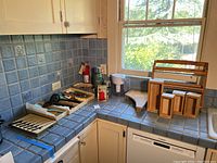 Full view of kitchen counter with various kitchen utensils and tools displayed including cutlery set, wooden containers, thermos bottles, and water filter pitcher.