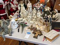 Full view of all religious themed Christmas decor items on the table including nativity figures, crosses, star ornament, and Santa figurines.