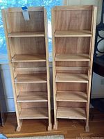 Front view of two wooden folding bookshelves with five shelves each, showing natural wood finish.