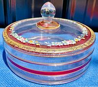 Side top view of the round glass covered dish with intricate floral enamel decoration, glass finial knob for lid.