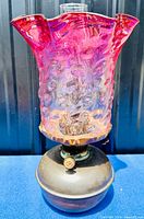 Full front view of Victorian ruby glass oil lamp showing ruby shade with bubble pattern and spherical ruby font on blue background.