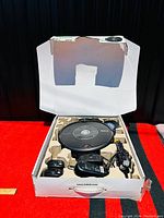 Overall view of the Roomba vacuum and accessories in box with open lid