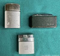 Three vintage lighters: one with leather wrap and CLAAS stamp, and two Ronson lighters, one engraved