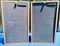 Front view of both speakers side by side with cloth grills installed showing cabinet finish and overall condition