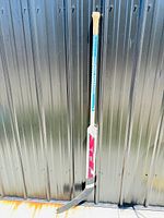 Full view of the signed hockey stick showing its length and taped handle.
