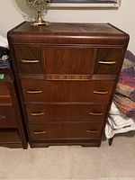 Front view of vintage Art Deco waterfall dresser showing four drawers with curved handles and veneer bubbling on the top surface.