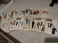 Photo showing a row of various vintage sewing patterns for women's and children's clothing including Butterick and Simplicity, mostly mid-20th century styles