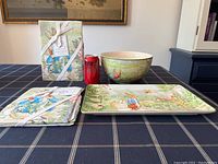 Photo of the large ceramic mixing bowl, rectangular serving tray, two packaged tea towels, and a soda can for scale on a checkered tablecloth