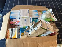 Open cardboard box filled with multiple unopened boxes of light bulbs from various brands.
