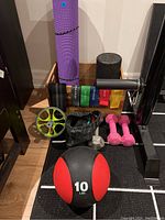 Overview of exercise and recovery items including yoga mat, foam roller, resistance bands, ab wheel, hand weights, massage ball, wooden storage box, and medicine ball.