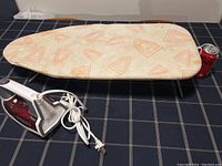 Black+Decker steam iron and compact ironing board with a soda can for scale.