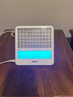 Front view of Philips GoLITE BLU HF3332 blue light therapy lamp showing illuminated control panel and grid light panel.