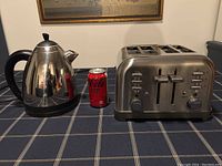 PC stainless steel kettle and Cuisinart four-slice toaster with a soda can for scale on a checkered tablecloth.