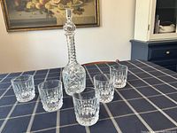 Full set on table: one decanter with stopper centered and five matching tumblers arranged around it