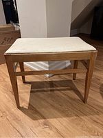 Front angled view of vintage wood bench with leather seat showing overall condition and finish.