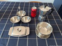 Photo of the full set including butter dish, three-section snack server, dip bowl with tray, stovetop espresso pot, and soda can for scale on a checkered tablecloth.