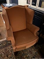 Front and angled view of vintage Vogel wingback chair showing upholstery detail and wooden legs.