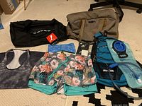 Photo showing all items including 2 Puma duffel bags, running shorts, workout tank, ear warmer, Adidas wrist bands, and Miracol hydration backpack with water bladder.