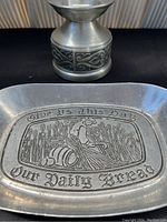 Close-up of the pewter bread server showing engraved phrase and detailed embossed design