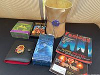 Entire lot arranged on a black surface showing Harry Potter books, cassette and CD cases, magazines, and the bathroom garbage bin.