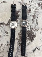 Two vintage Harry Potter themed watches with black straps on a light marbled surface.