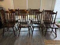 Eight solid wood dining chairs arranged in a row, showing full ensemble