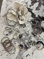 Full lot laid out on a rug showing assortment of bracelets, rings, earrings, and necklaces
