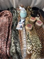 Four animal print scarves and packaged nighty, three animal print candles, ceramic wax diffuser with wax cubes arranged on scarves.