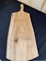 Full view of wooden live edge charcuterie board, showing overall shape and handle