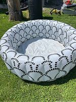 Full view of inflatable pool placed on grass, showing white with black fan design pattern