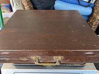 Closed wooden case with brass handle showing some wear.