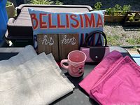 Overview of lot items including the Bellisima pillow, his and hers hooks, Disney Minnie mug, pink fold-up bag, pink pillow shams, and beige window sheers.