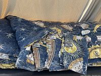 Photo of folded queen size comforter showing astrology pattern with zodiac signs, moons, and suns.