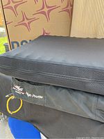 Two black ROHO Airlite cushions stacked with a box in the background displaying ROHO branding and product line.
