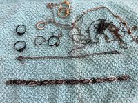 Photo showing Siam sterling silver bracelet with intricate black and silver inlay and multiple loose jewelry bits including broken chains, rings, and a pair of gold-tone earrings.