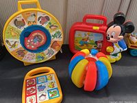 Full view of the collection showing Shelcore build-a-ball, Fred Toy animal sound board, Disney Mickey Mouse music toy and colorful ball toy.